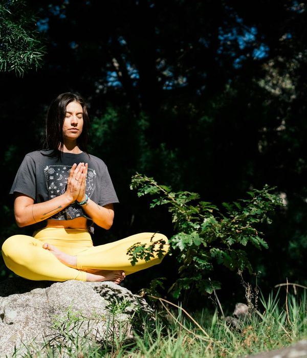 Person sitting in a cross-legged position with eyes closed, embodying peace.